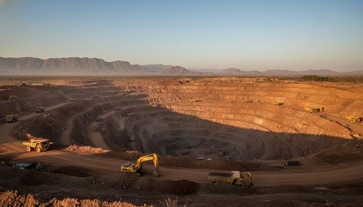 Крупный карьер золотодобывающего рудника в Зимбабве на начальном этапе разработки. На террасах стоит тяжелая горная техника.