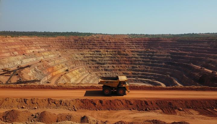 Гана удвоит роялти для золотодобытчиков: инвесторы бьют тревогу Огромный карьер золотодобывающего рудника в Гане с террасными уступами и крупной горнодобывающей техникой.