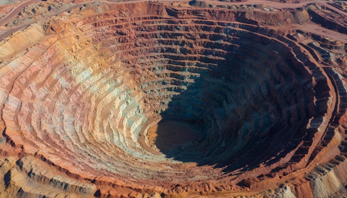 Огромный карьер по добыче меди с высоты птичьего полета, разноцветные террасы и геологические пласты породы.
